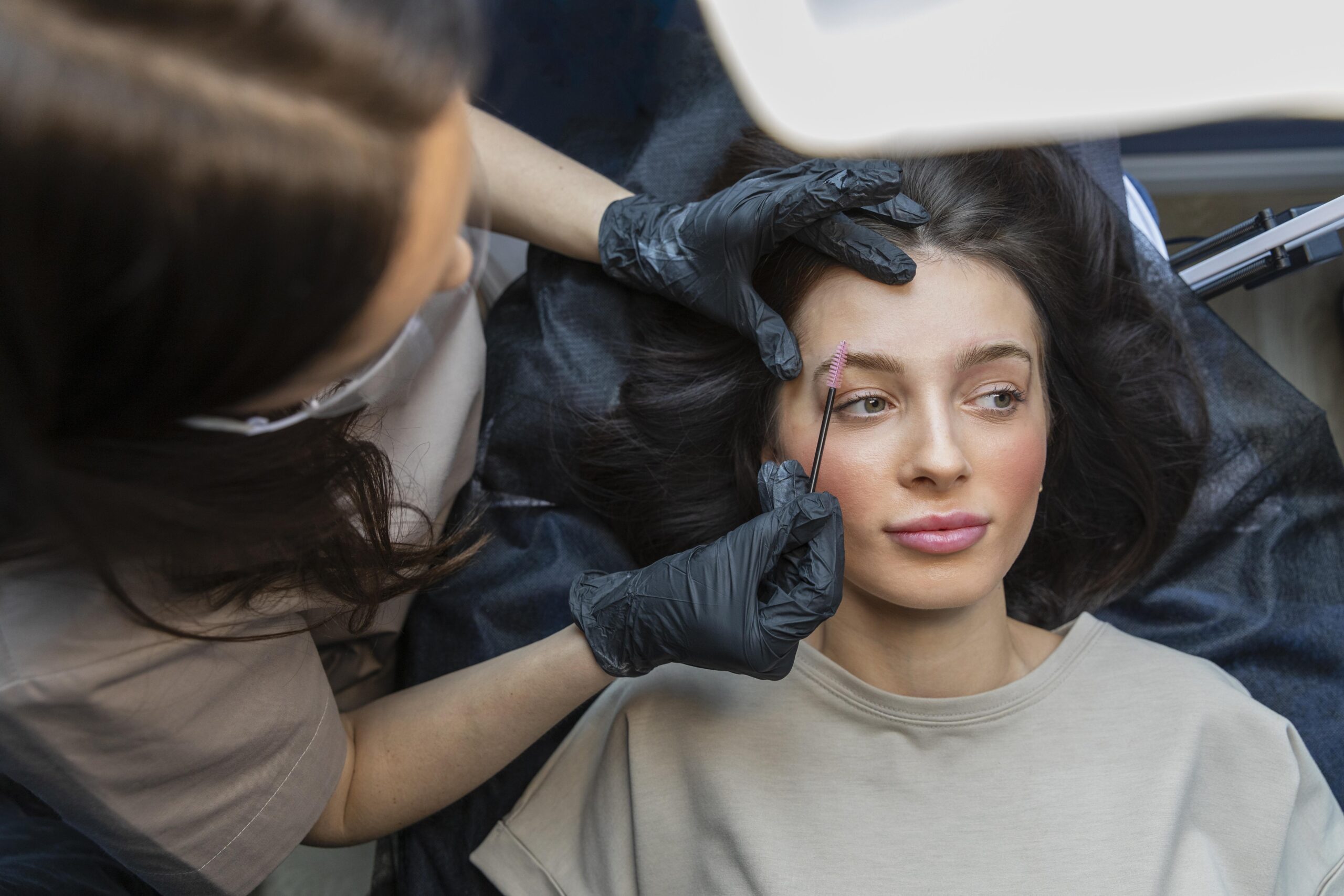 Custom eyebrow shape threading: technician marking custom brow shape points on client