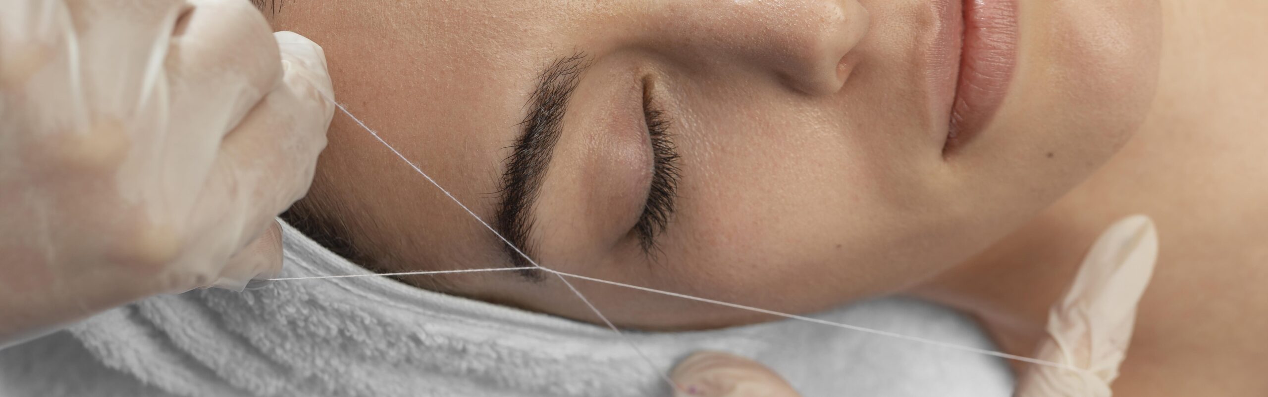 How long does eyebrow threading last: technician performing precise eyebrow threading with thread