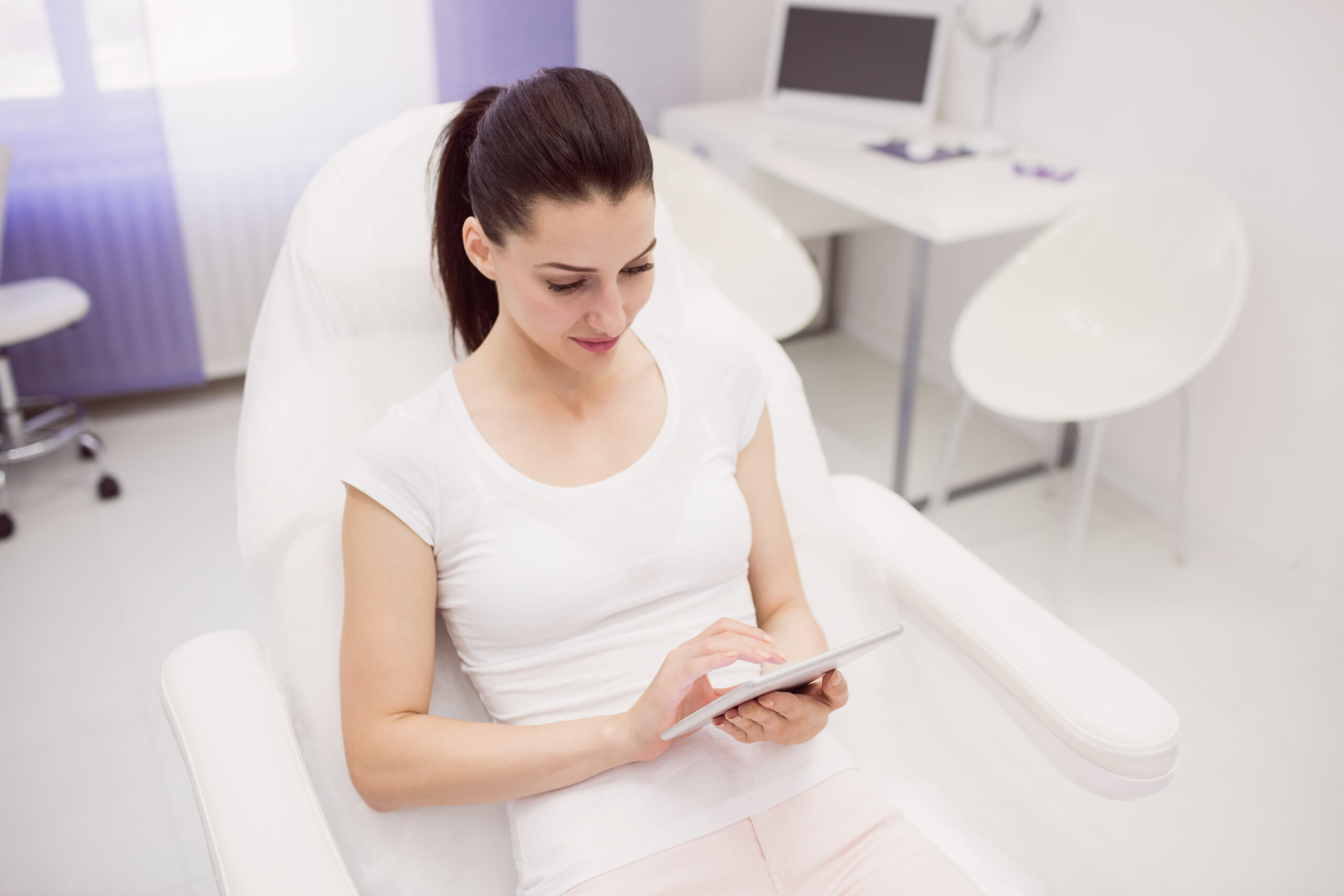 Client reviewing treatment information on a tablet in a Brooklyn laser clinic
