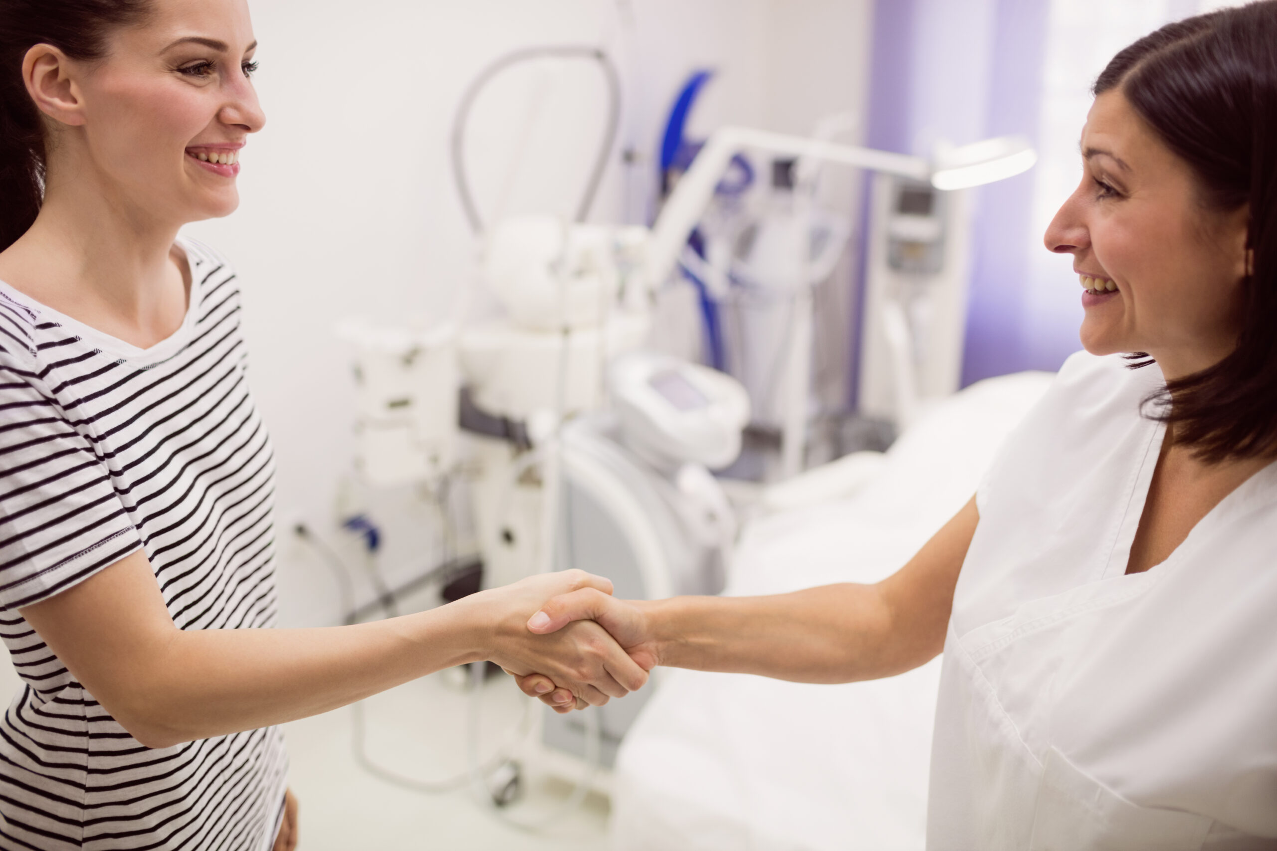 Doctor shaking hands with a smiling patient in a Brooklyn clinic treatment room