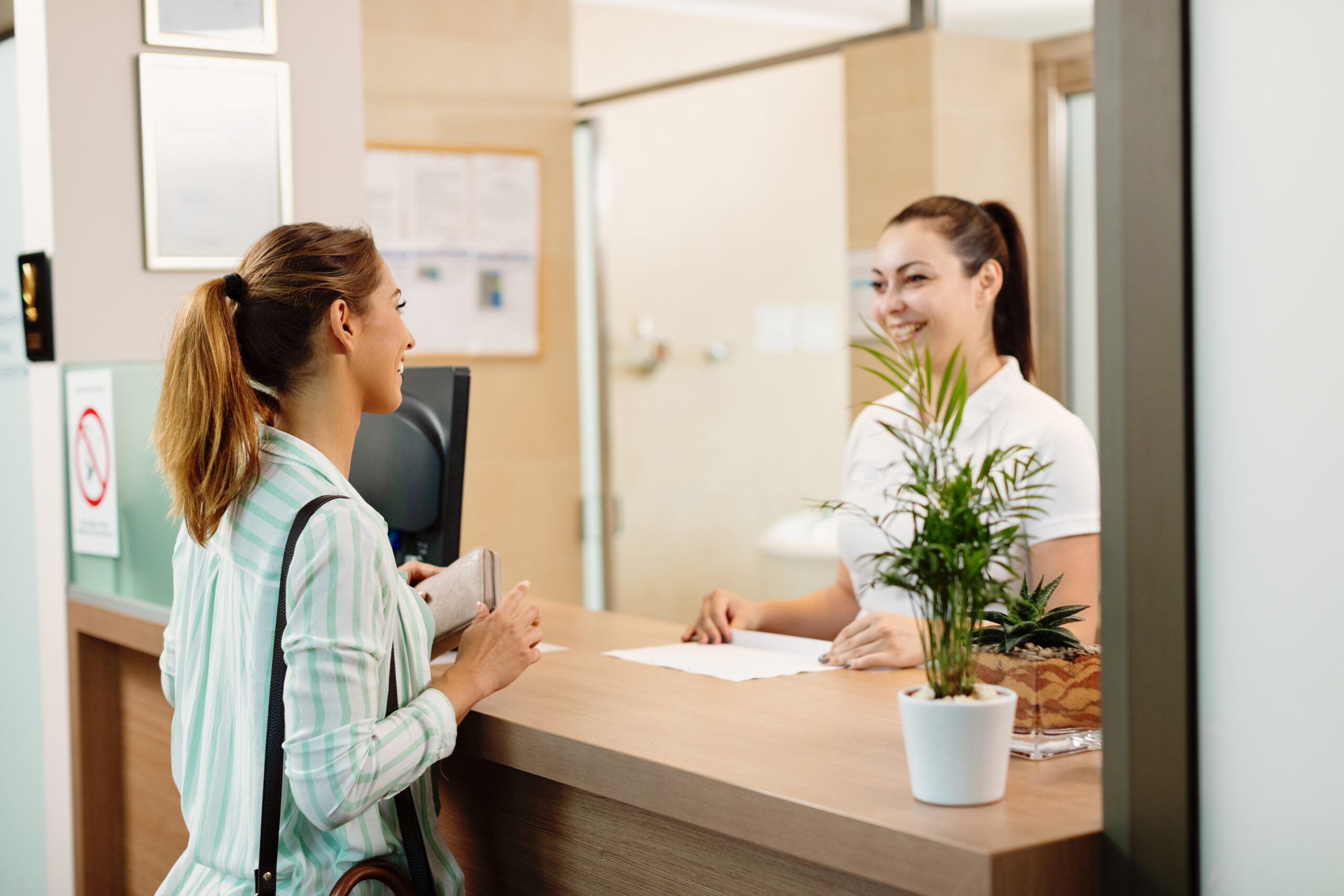 Happy client speaking with a receptionist at a Brooklyn laser hair removal clinic