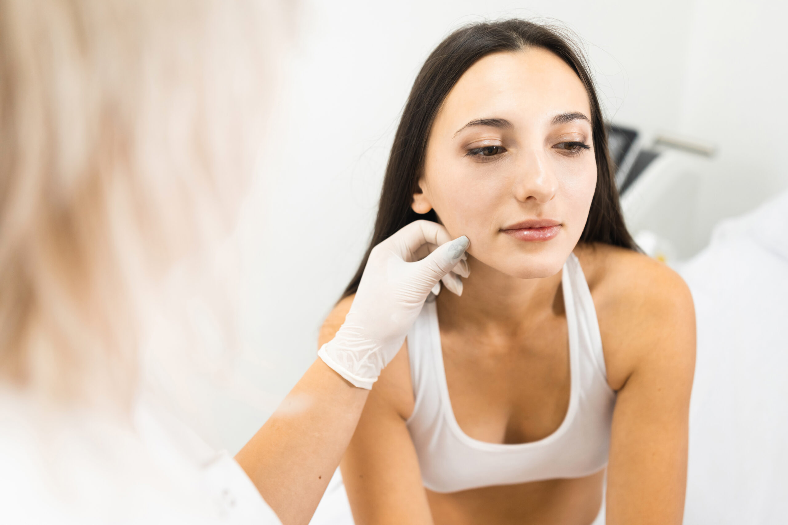 Provider in gloves examining a client's skin during a consultation before laser hair removal at a Brooklyn clinic