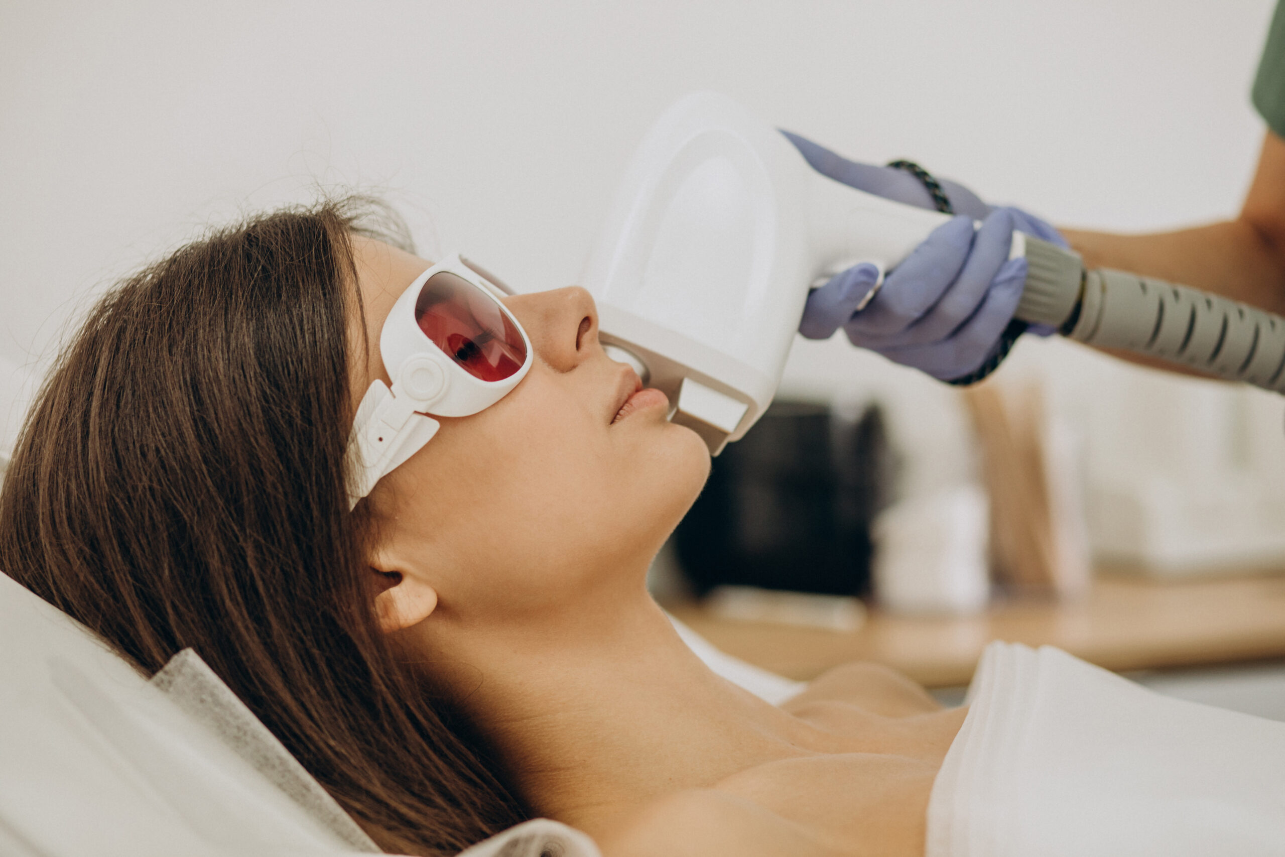 Woman wearing protective glasses during a gentle facial laser hair removal treatment at a Brooklyn clinic