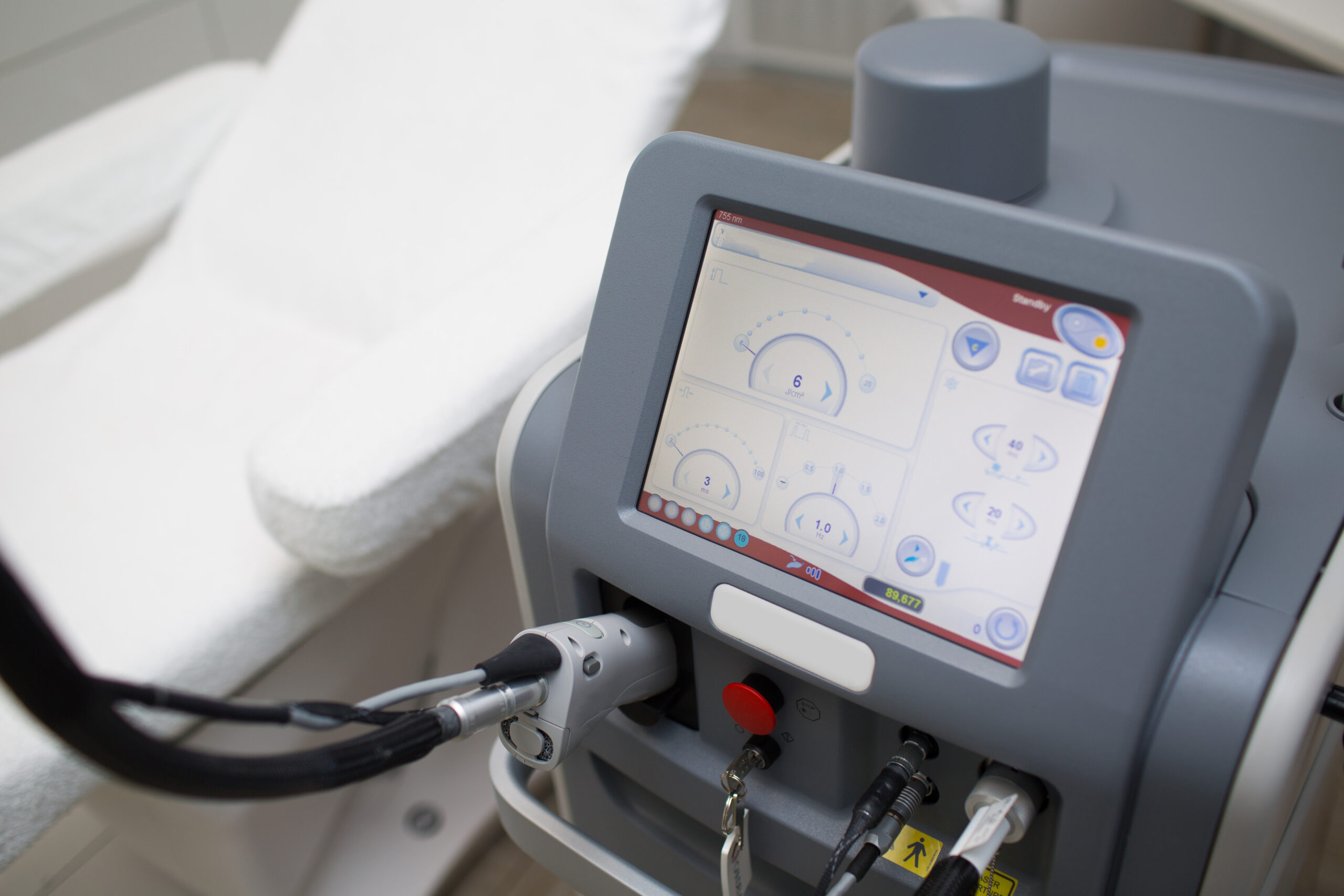 Laser hair removal device with handpiece positioned next to a treatment chair in a Brooklyn clinic