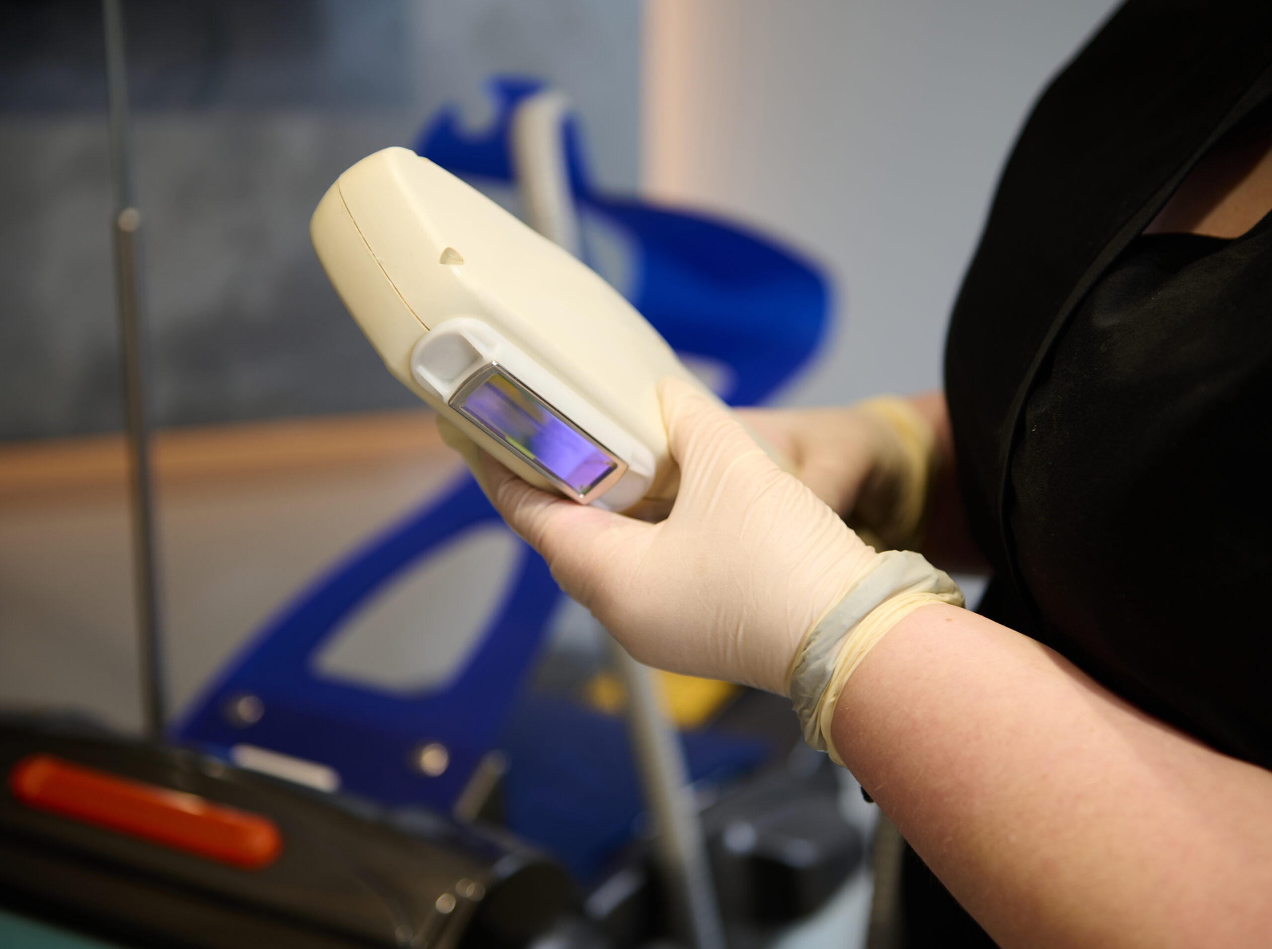Gloved technician holding a laser hair removal handpiece during treatment at a Brooklyn clinic