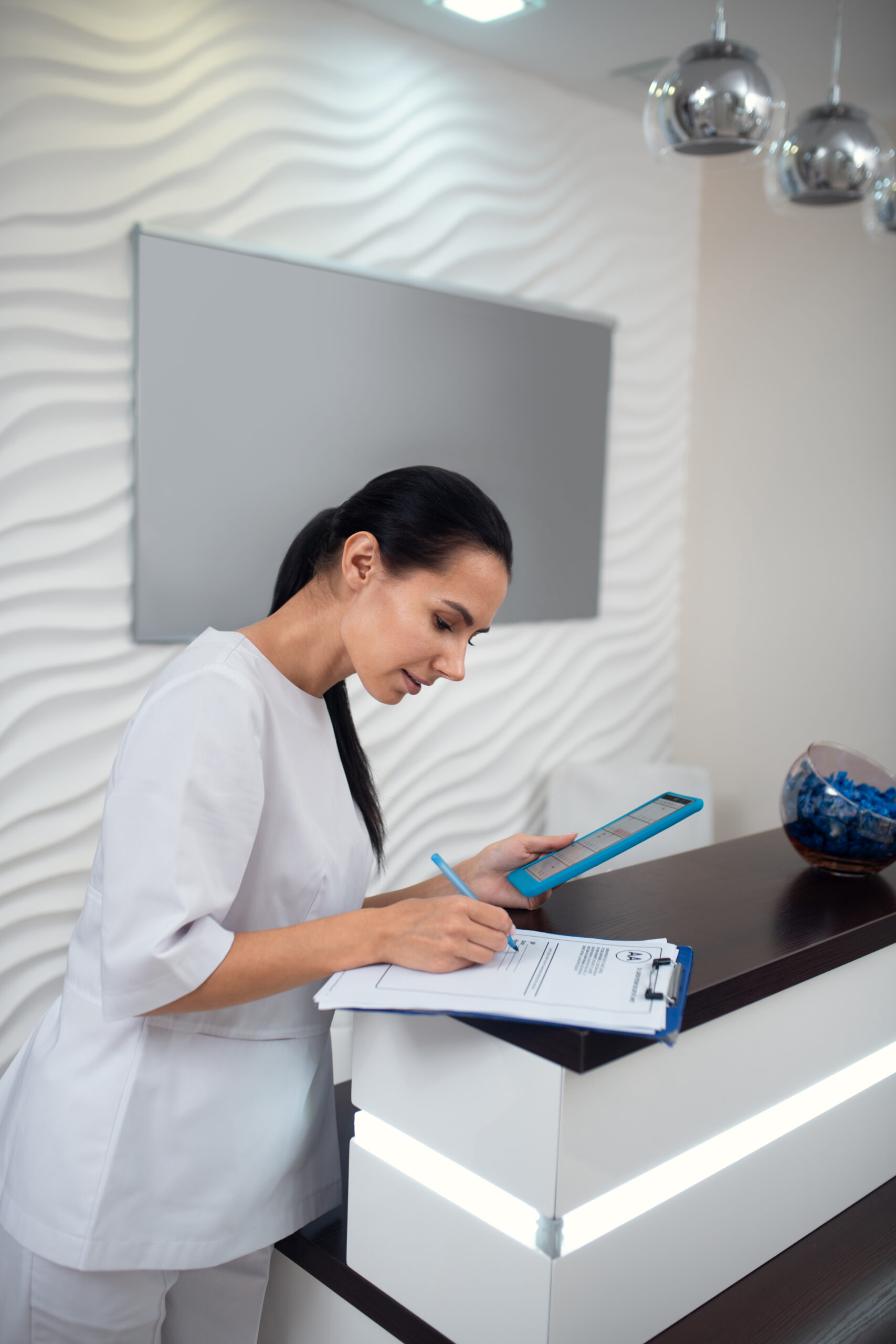 Receptionist helping a client book a same-week laser hair removal appointment at a Brooklyn clinic