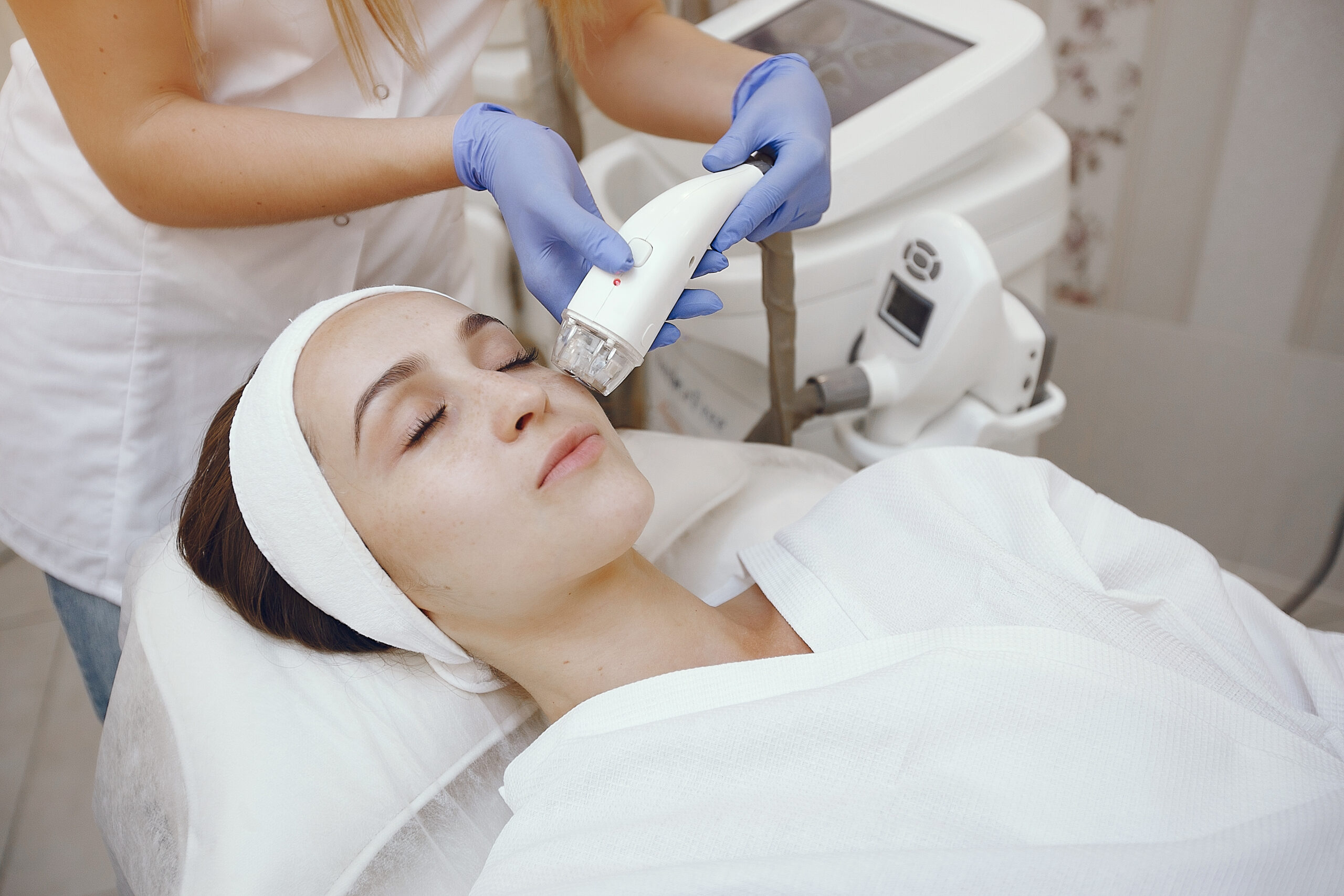 Technician using a laser device during a facial treatment at a Brooklyn clinic