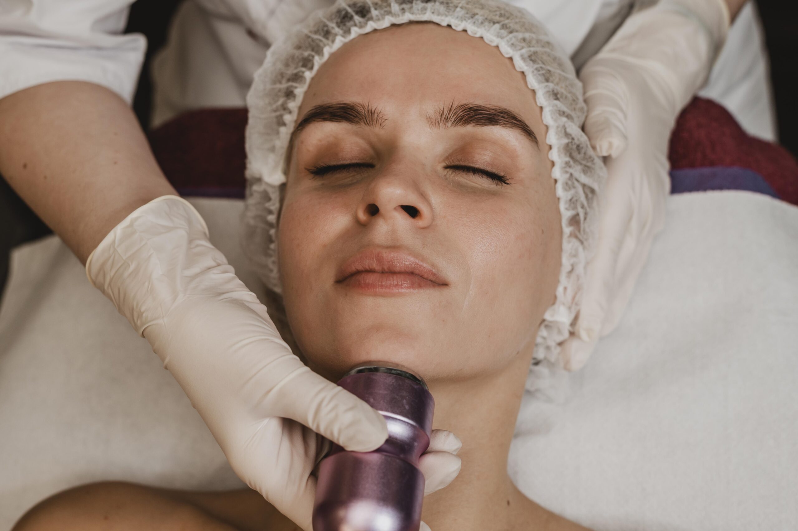 Gloved provider performing a laser skin treatment on a client's face at a Brooklyn clinic