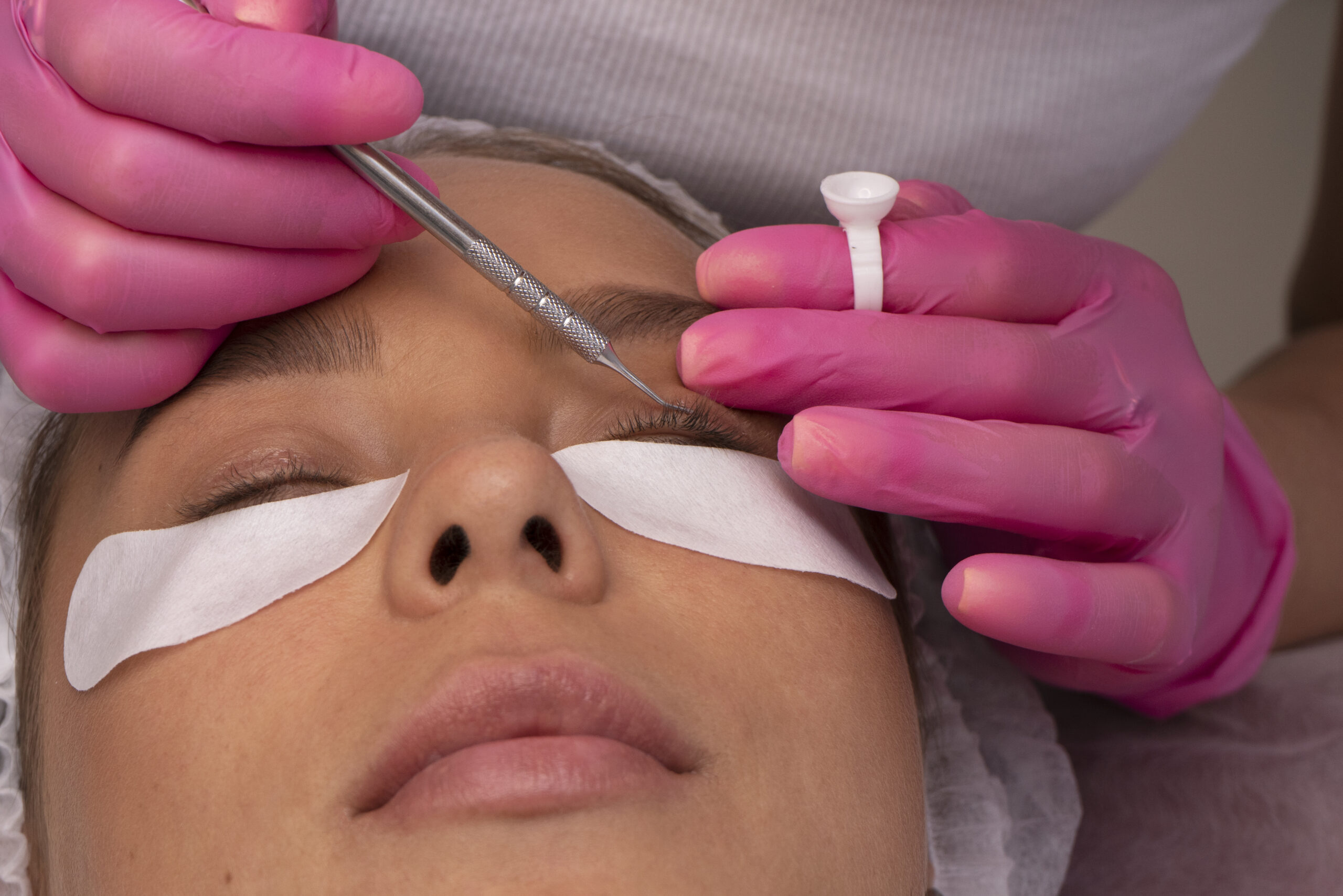 Causes of lash extensions falling out early, technician checking lash line during treatment