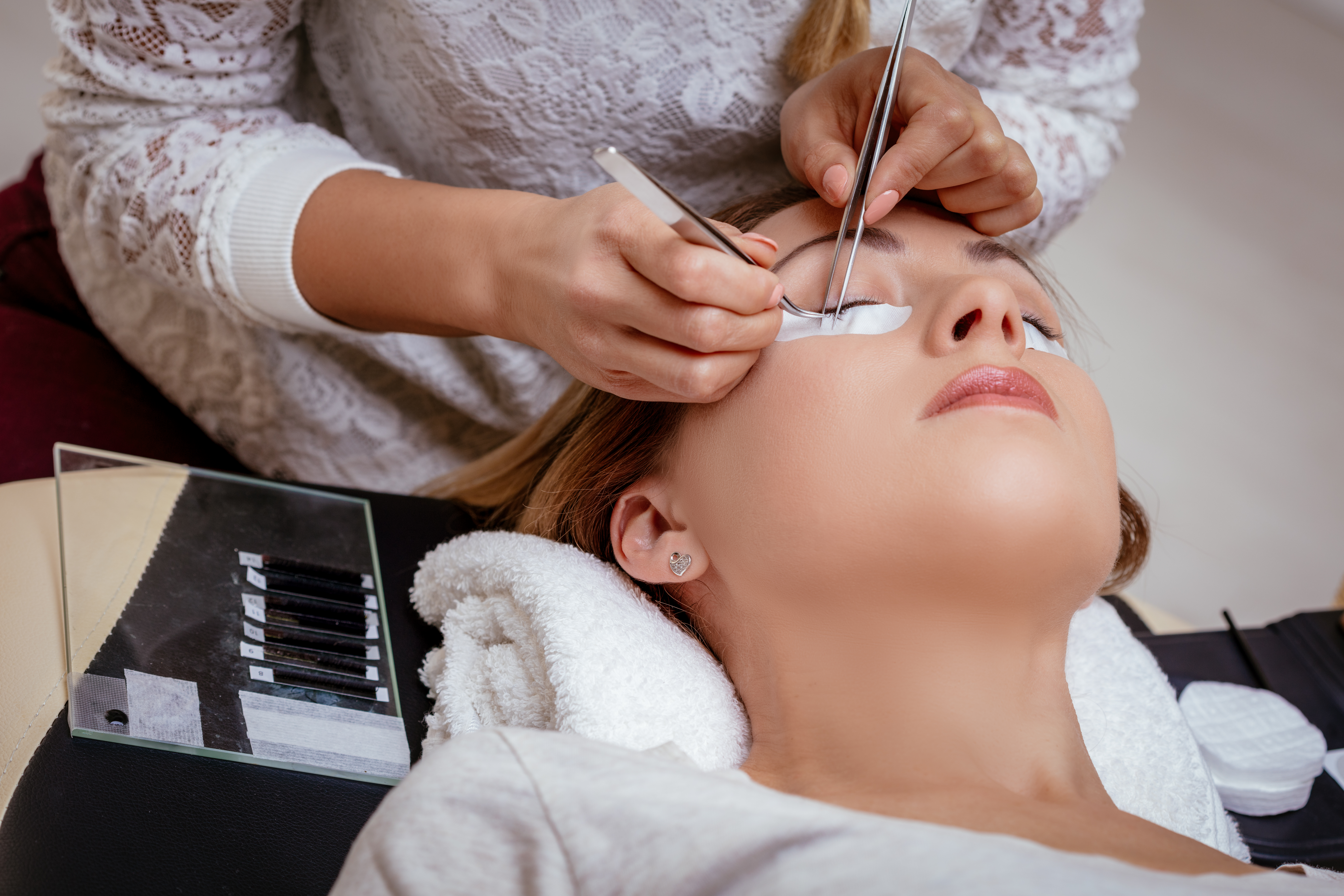 Difference between a lash fill and a full new set, technician examining existing lash extensions