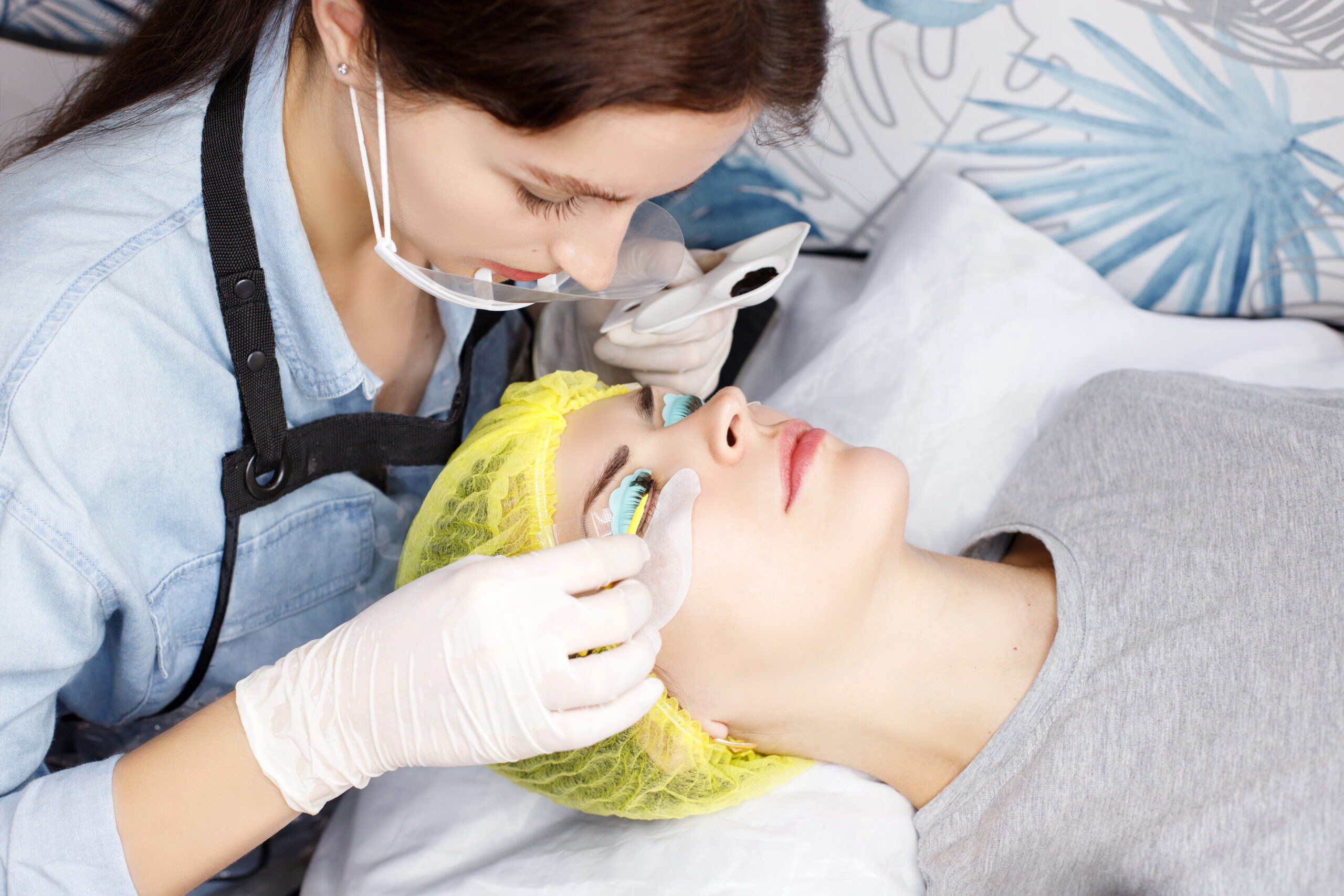 Combining lash extensions with lash tinting, technician performing lash lamination and tint procedure