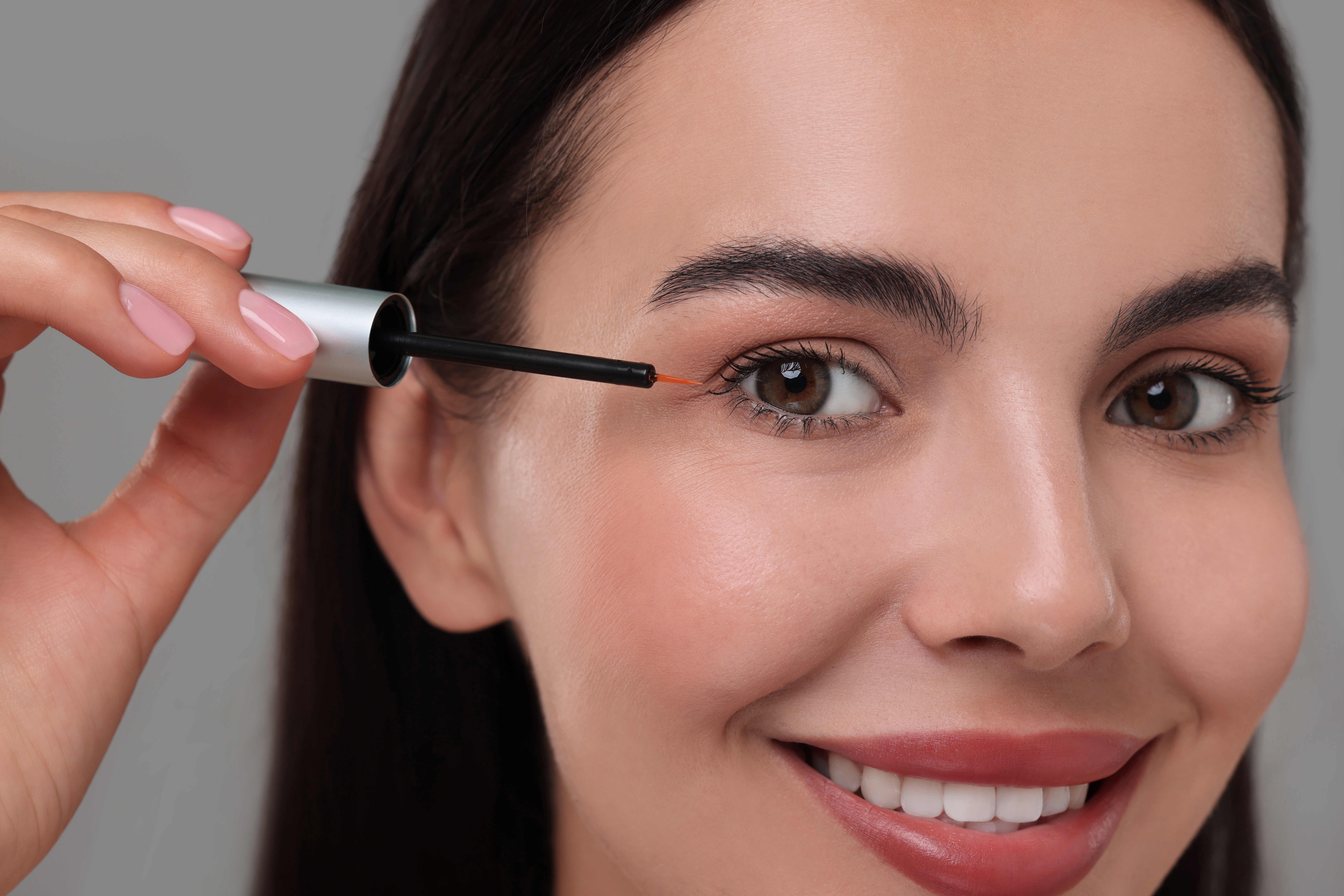 Lash serum application for lashes with extensions, closeup of serum wand near eyelash line